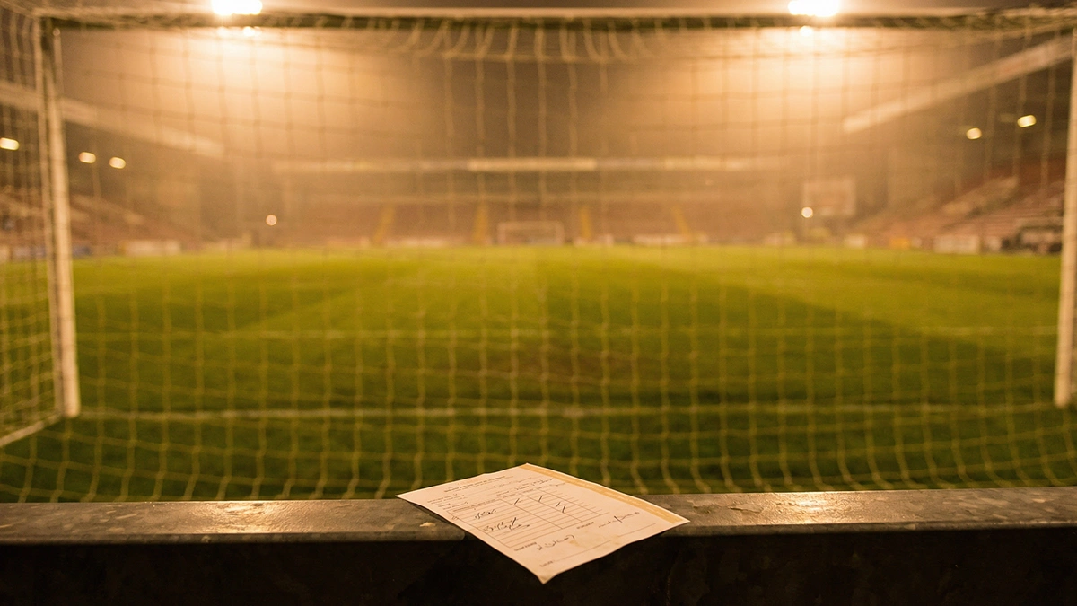 Coupon de pari combin&eacute; sur fond de stade de football &eacute;clair&eacute; en soir&eacute;e